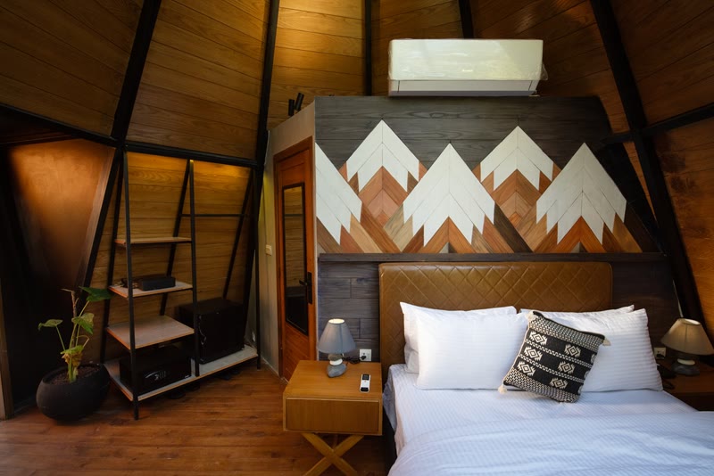 A-frame cabin bedroom with a wooden mountain mural above the bed