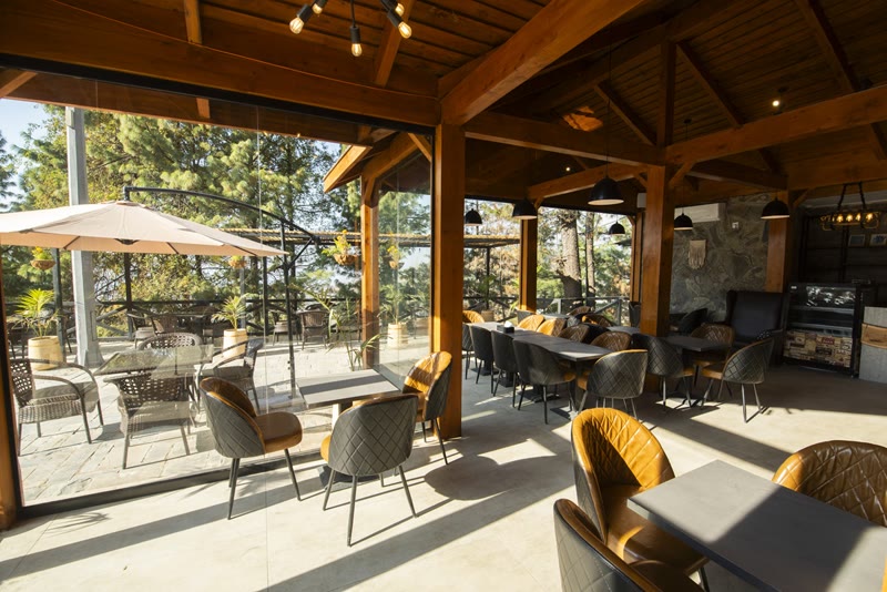 Covered dining terrace with timber beams and forest views