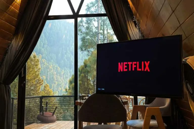 Forest valley view through the window of a glamp, with a TV and seating