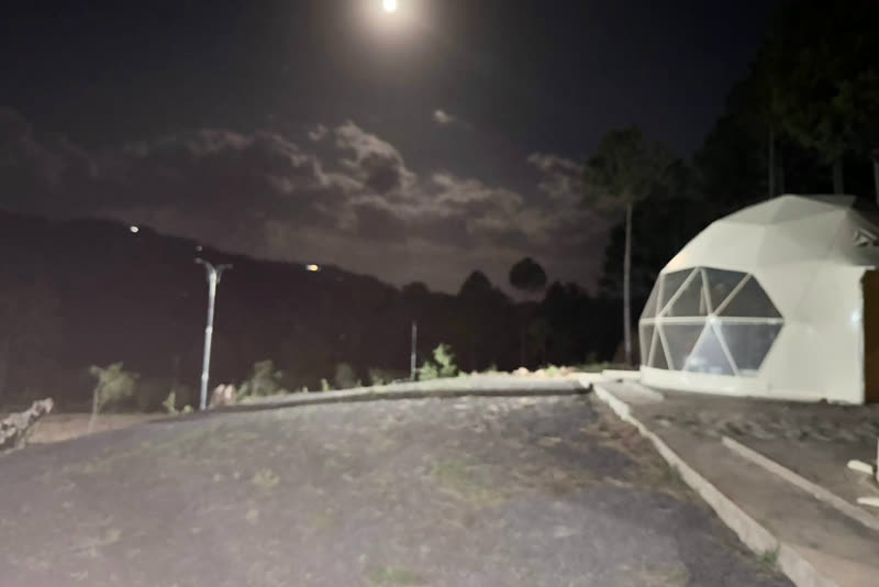 A glamping dome on the hillside under a moonlit sky