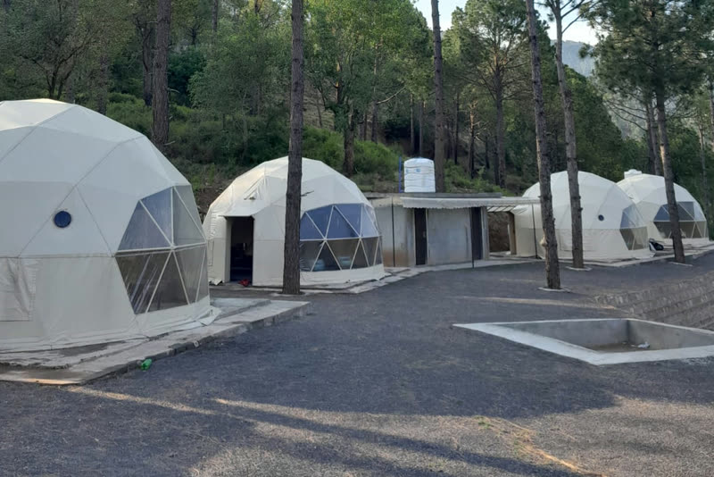 White geodesic glamping domes among pine trees at Taskeen E Rooh